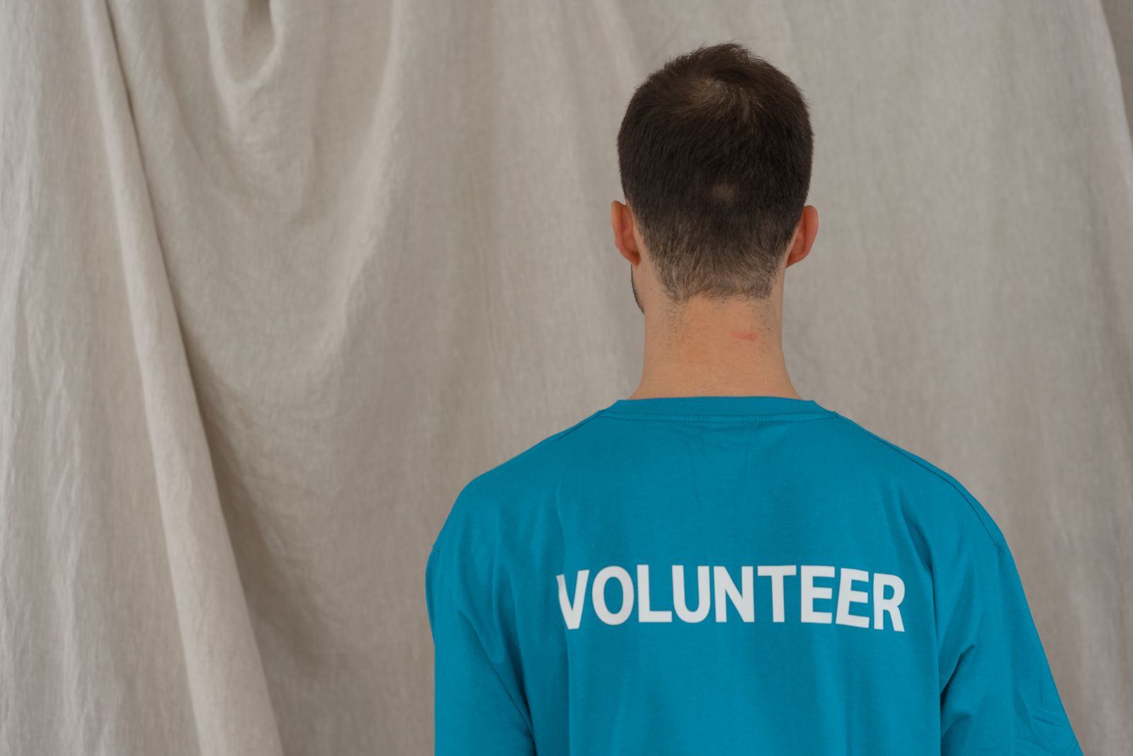 A volunteer in a blue team shirt, seen from behind
